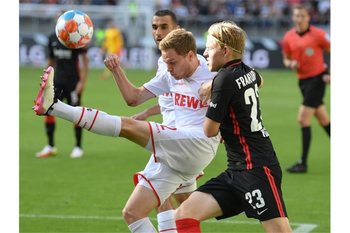 Kölns Benno Schmitz (l) kommt vor Frankfurts Jens Petter Hauge an den Ball. Foto: Arne Dedert/dpa