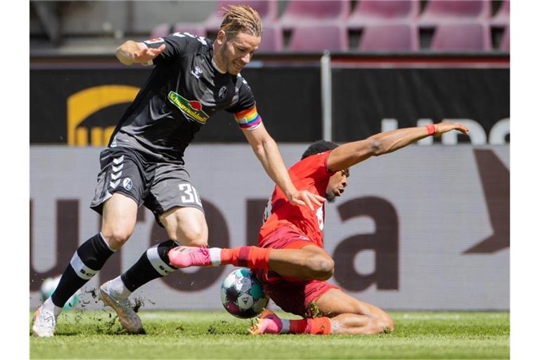 Kölns Kingsley Ehizibue (r) und Freiburgs Christian Günter versuchen an den Ball zu kommen. Foto: Rolf Vennenbernd/dpa
