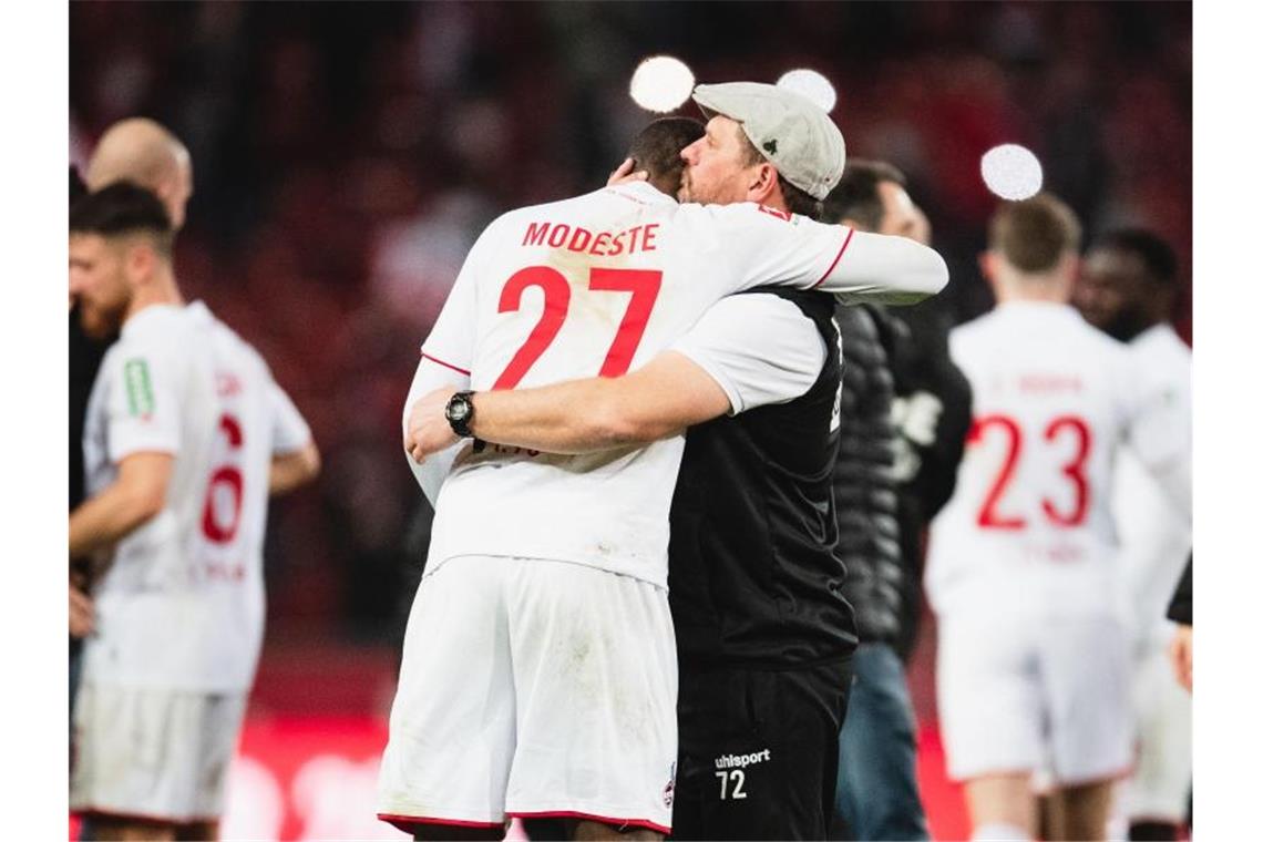 Kölns Matchwinner Anthony Modeste (l) weinte im Arm von Trainer Steffen Baumgart. Foto: Marius Becker/dpa