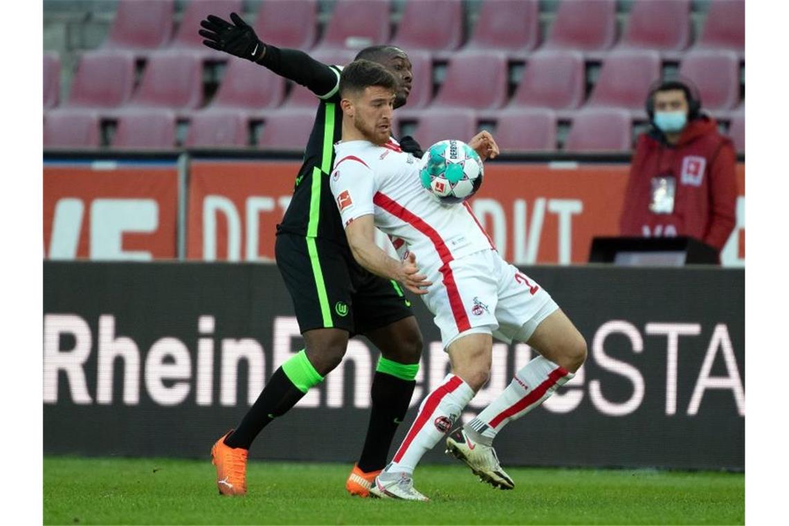 Remis im Gipfel zwischen Bayern und Leipzig - BVB enttäuscht Kölns Salih Özcan (r) schirmt das Spielgerät geschickt mit dem Körper vor dem Wolfsburger Jerome Roussillon ab. Foto: Federico Gambarini/dpa-Pool/dpa