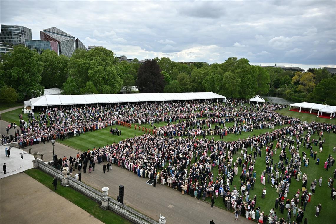 König Charles III. und Königin Camilla (unten links) stehen vor dem Beginn einer königlichen Gartenparty im Buckingham Palace, London, an der Spitze der Gartentreppe.