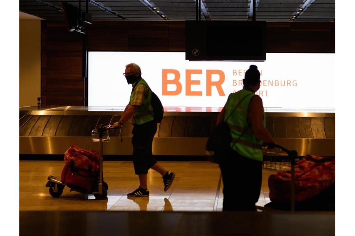 Komparsen in Warnwesten gehen beim Probelauf im Terminal 1 des Hauptstadtflughafens Berlin-Brandenburg (BER) mit ihren Koffern zum Check in. Foto: Soeren Stache/dpa-Zentralbild/dpa
