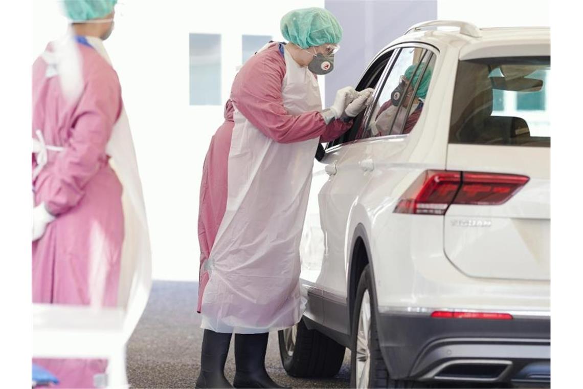 RKI: Coronavirus-Sterberate in Deutschland wird steigen Konzipiert für Drive-in und Walk-in: Eine Mitarbeiterin mit Mundschutz und Schutzkleidung entnimmt bei einem Autofahrer in Heidelberg eine Probe. Foto: Uwe Anspach/dpa