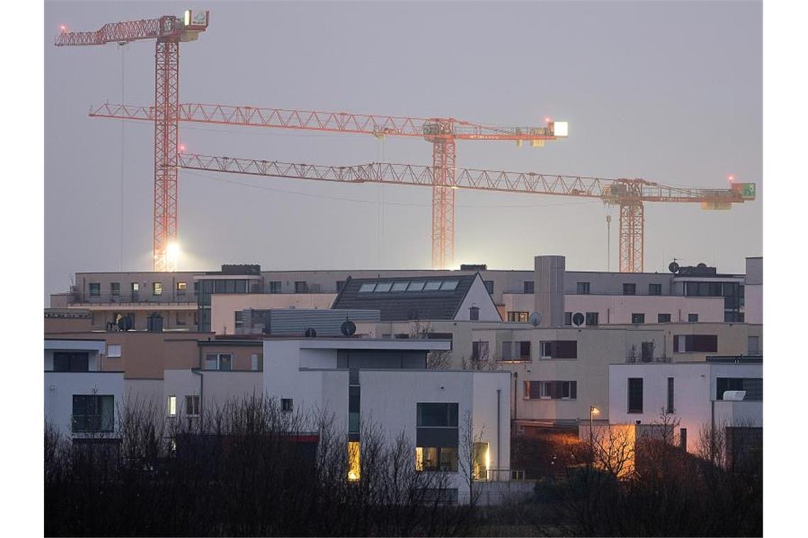 Schlagabtausch zu den Bau-Plänen der Regierung im Bundestag Kräne auf einer Baustelle für Wohnungen stehen hinter Mehrfamilienhäusern des relativ neuen Stadtteils Kalbach-Riedberg in Frankfurt. Foto: Sebastian Gollnow/dpa