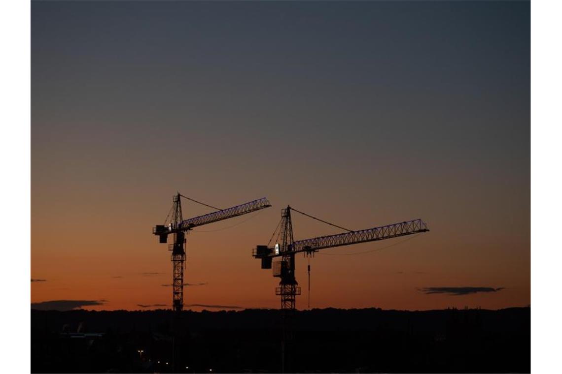 Kräne vor dem Abendhimmel auf einer Baustelle: Die Wirtschaftsstimmung steigt. Foto: Robert Michael/dpa-Zentralbild/dpa