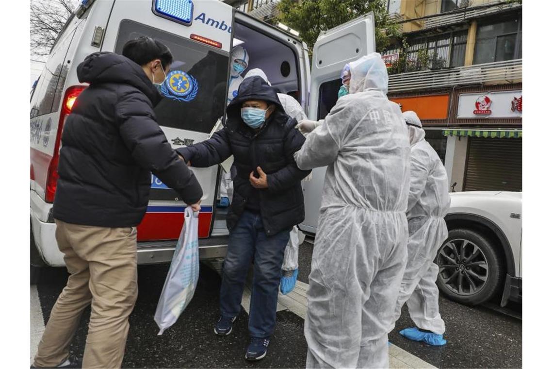 Krankenhausmitarbeiter in Wuhan helfen einem Patienten aus einem Krankenwagen. Foto: Uncredited/CHINATOPIX/AP/dpa