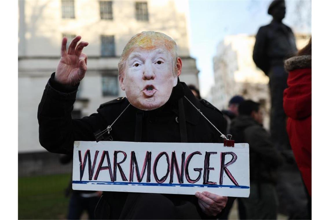 „Kriegstreiber“ steht auf einem Schild, das ein Demonstrant mit Trump-Maske bei einem Protest in London hält. Foto: Yui Mok/PA Wire/dpa