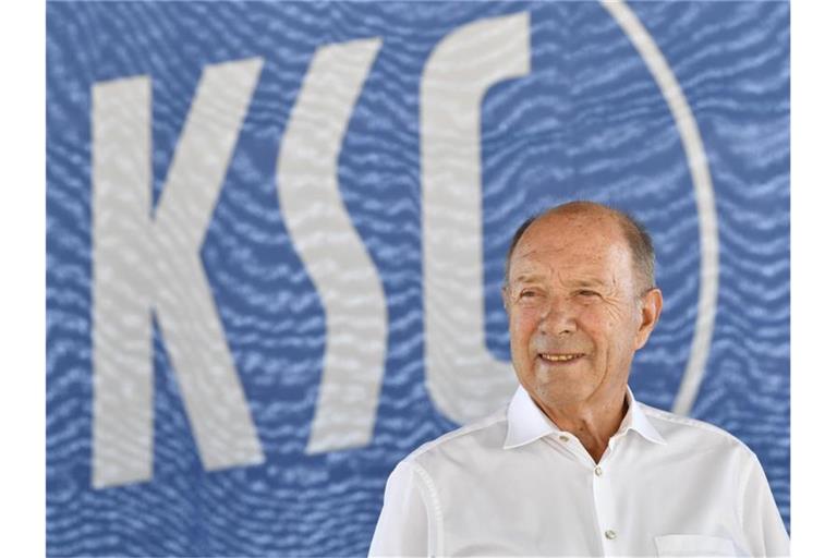 KSC-Vizepräsident Günter Pilarski lächelt auf dem Podium vor dem Vereinslogo. Foto: Thomas Kienzle/Archivbild