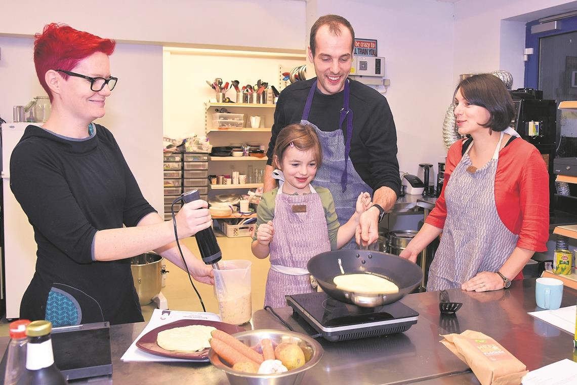 Küchenfee Zsuzsa Banvölgyi-Stadler (links) und Klimafamilie Sator kochen gemeinsam vegan. Hier fliegt gleich der Pfannkuchen. Foto: T. Sellmaier