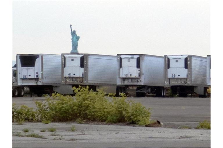Kühlwagen zur Lagerung von Corona-Toten stehen auf einem Parkplatz am Pier im Stadtteil Brooklyn. Foto: Ted Shaffrey/AP/dpa