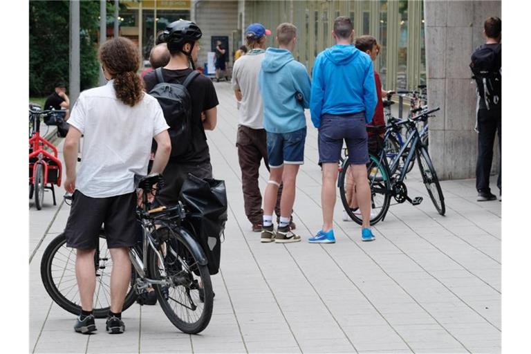 Kunden einer Fahrradwerkstatt stehen vor der Tür des Geschäftes in einer Schlange an. Foto: Sebastian Willnow/dpa-Zentralbild/dpa