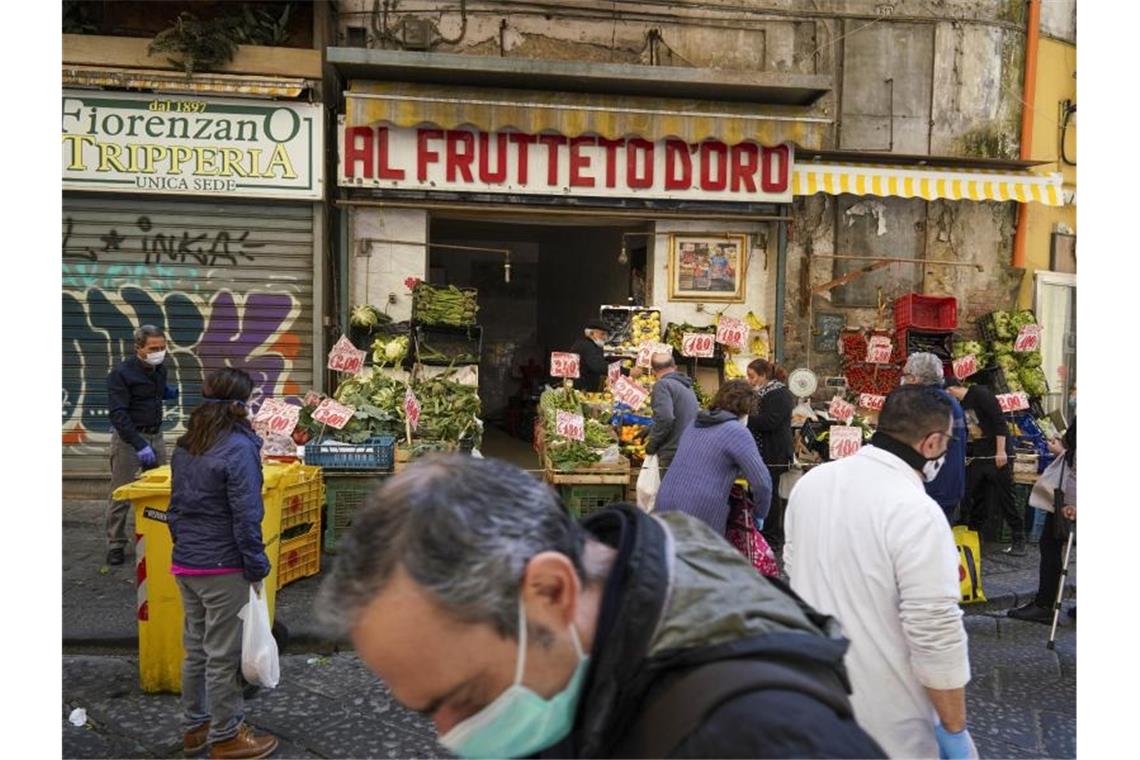 Kunden mit Mundschutz kaufen in einem Geschäft in Neapel Obst und Gemüse. Foto: Andrew Medichini/AP/dpa
