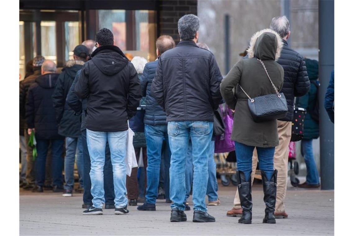 Kunden stehen am frühen Morgen kurz vor Öffnung vor einem Aldi-Markt. Foto: Julian Stratenschulte/dpa