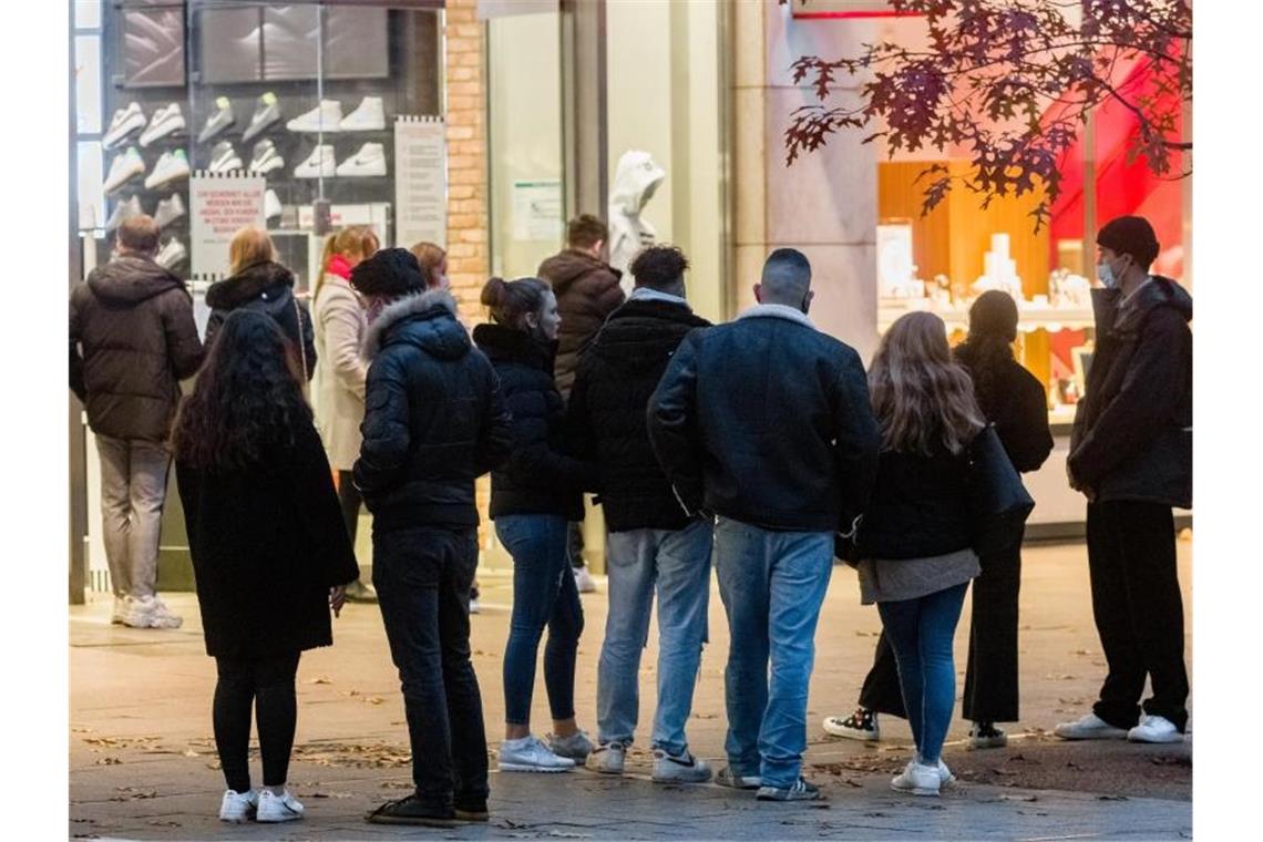 Kunden warten in der Mönckebergstraße in Hamburg in einer Warteschlange, bis sie in kleinen Gruppen einen Laden betreten dürfen. Foto: Markus Scholz/dpa
