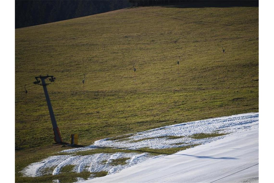 Kunstschnee liegt am Schneeberglift zwischen grünen Wiesen und Wäldern. Foto: Patrick Seeger/dpa