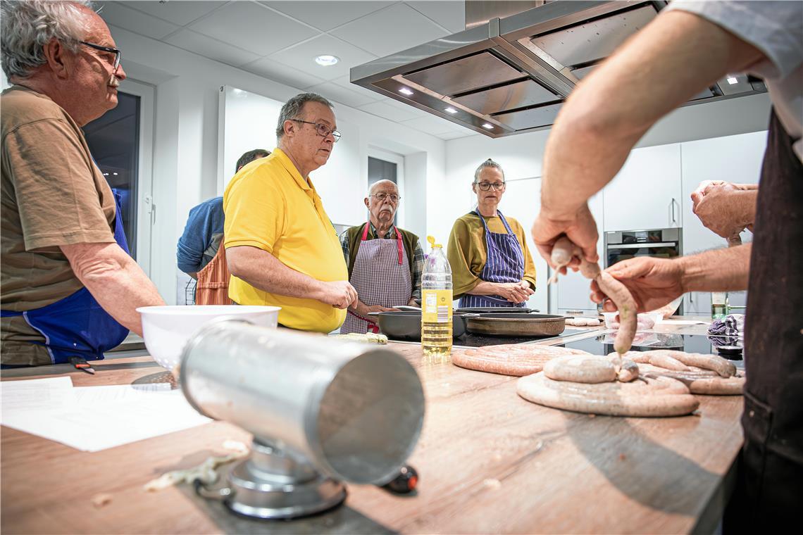 Kursleiter Stefan Hoffmann (in Gelb) weist die Teilnehmer in die Kunst des Wurstmachens ein. Fotos: Alexander Becher