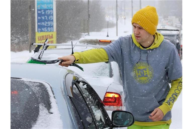 Kurz vor der Fahrt: Ein Mann wischt Schnee von seinem Auto. Foto: Vladimir Gerdo/TASS/dpa
