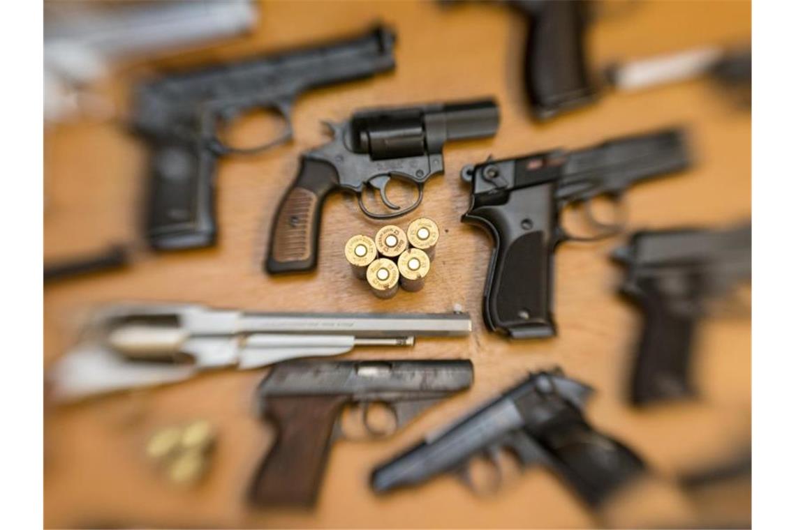 Kurzwaffen (Pistolen und Revolver) und Munition liegen auf einem Tisch. Foto: Friso Gentsch/Archiv