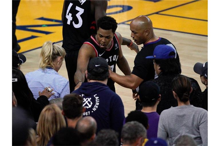 Kyle Lowry (M) von den Toronto Raptors beschwert sich neben Schiedsrichter Marc Davis über einen Fan. Foto: Tony Avelar/FR155217 AP/