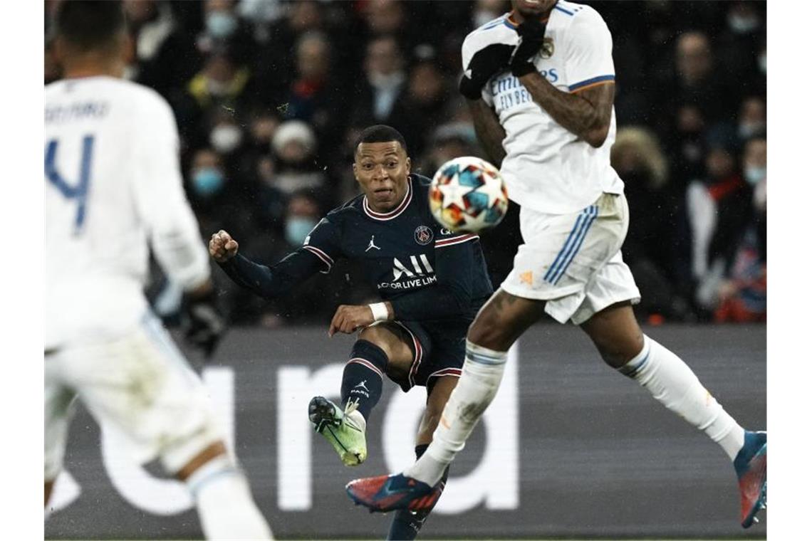 PSG dank Mbappé auf Kurs Viertelfinale - Kantersieg für City Kylian Mbappe (M) von Paris Saint-Germain (M) kommt gegen einen Abwehrversuch von Reals Eder Militao zum Schuss. Foto: Thibault Camus/AP/dpa