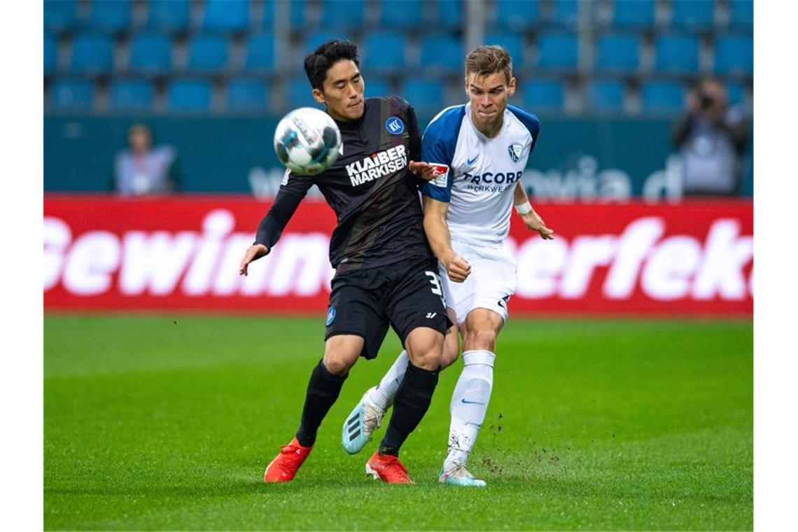 Kyoung-rok Choi vom Karlsruher SC und Bochums Simon Lorenz (l-r.) im Zweikampf um den Ball. Foto: Guido Kirchner/dpa