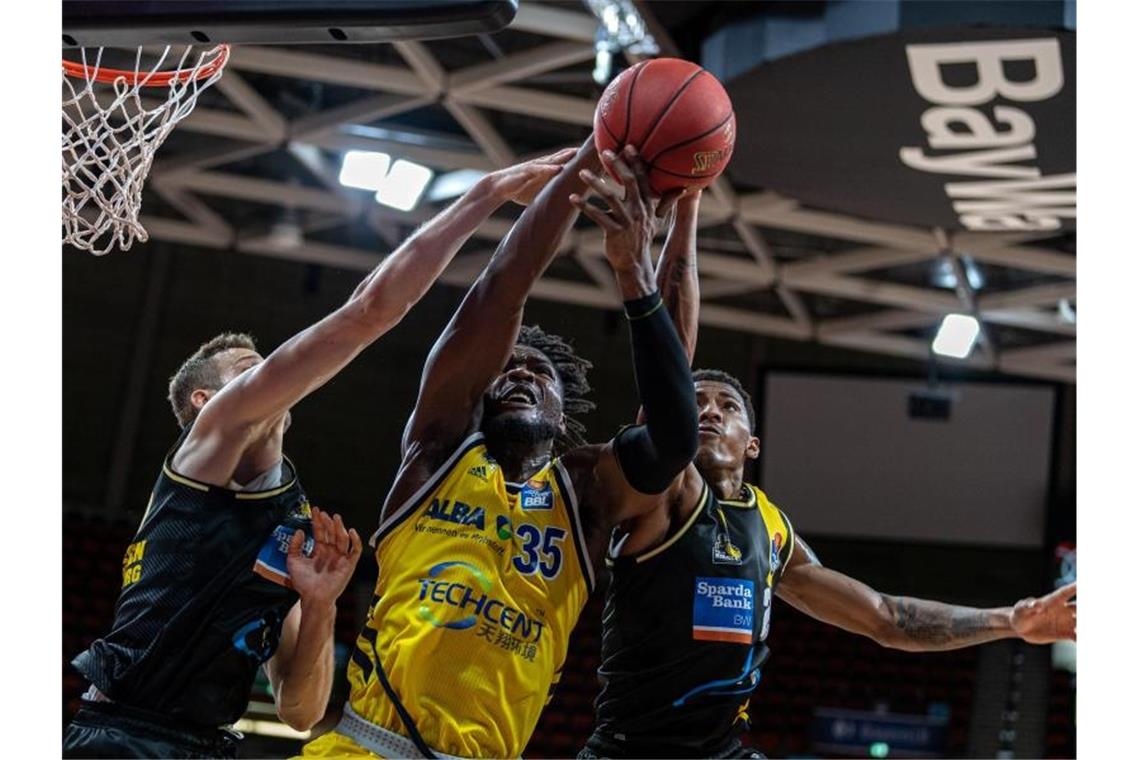 Landry Nnoko (M) von Alba Berlin setzt sich im Vorrundenspiel gegen zwei seiner Gegenspieler durch. Foto: Tilo Wiedensohler/camera4/BBL/pool/dpa