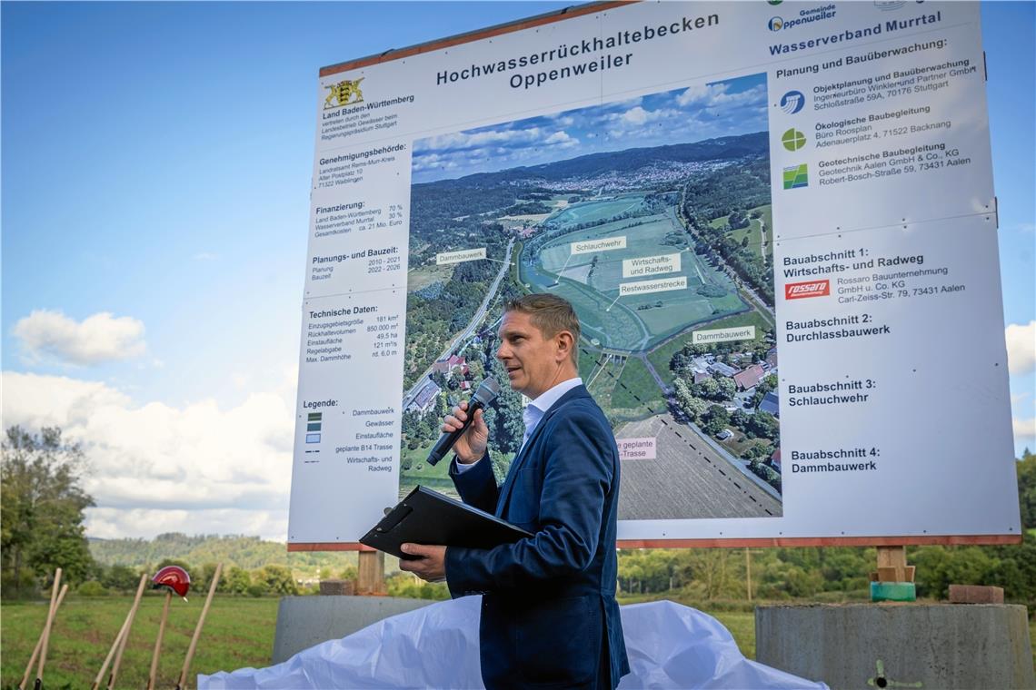 Lars Kaltenleitner, der Leiter des Backnanger Tiefbauamts, erklärt die Bauabschnitte und die technischen Daten des Hochwasserrückhaltebeckens Oppenweiler anhand des großen Bauschilds, das bei der Rüflensmühle steht. Foto: Alexander Becher