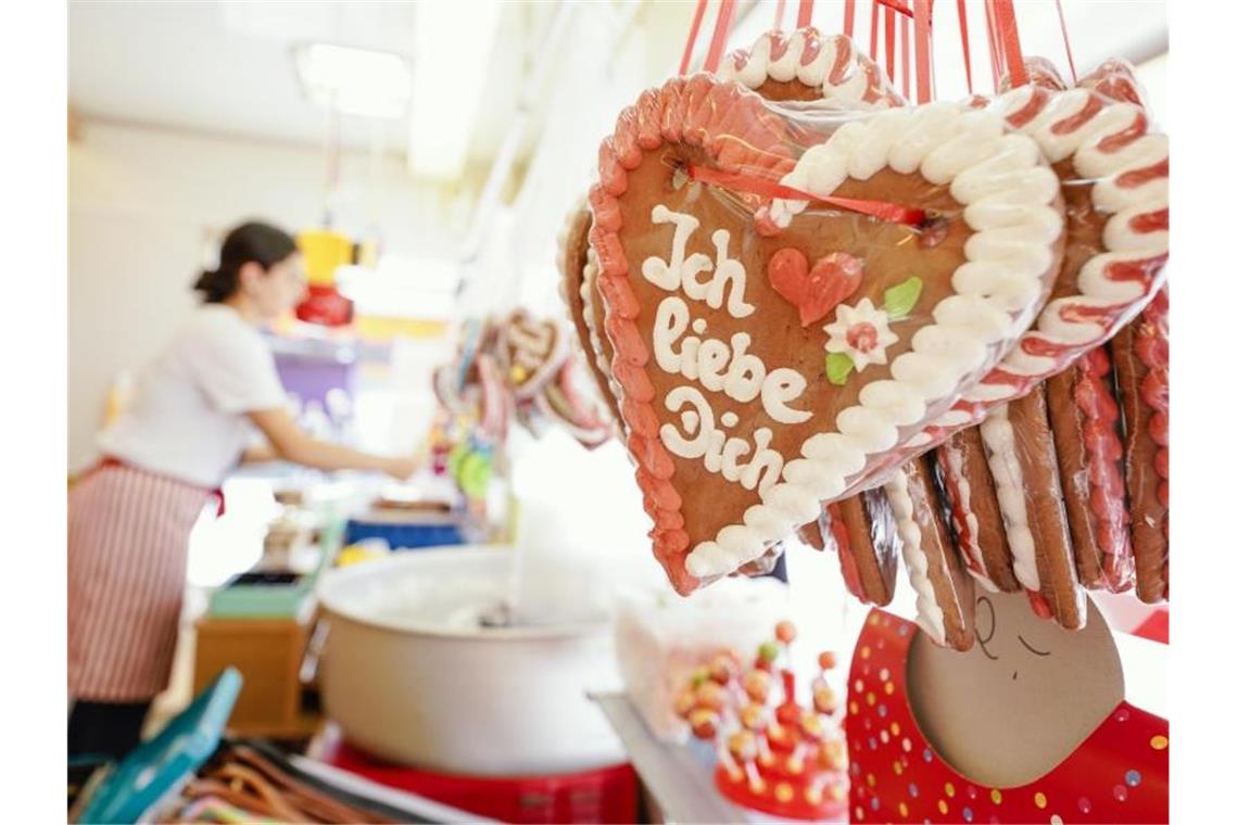 Lebkuchenherzen mit der Aufschrift „Ich liebe dich“ hängen in einem Schaustellerwagen. Foto: Uwe Anspach/dpa