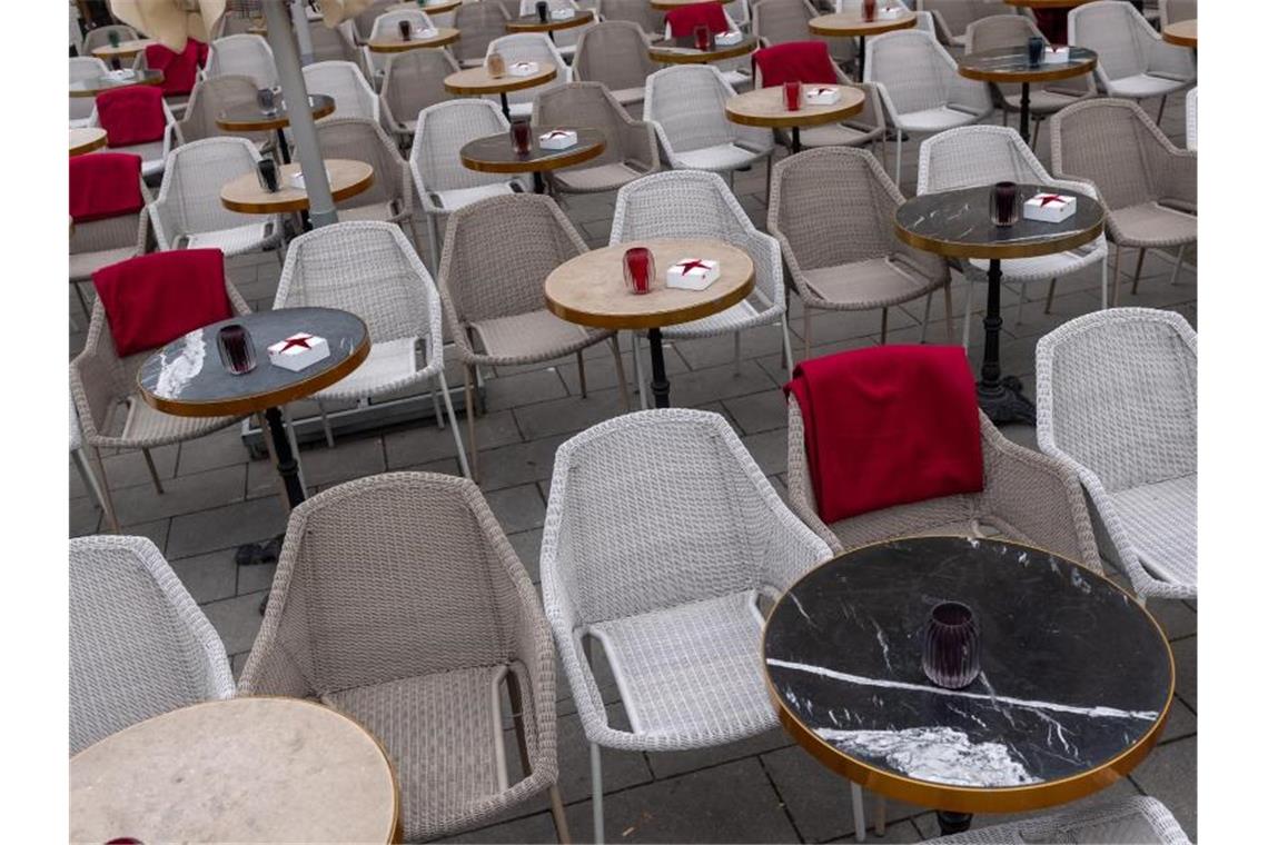 Leere Stühle vor einem Straßencafé. Foto: Peter Kneffel/dpa/Symbolbild