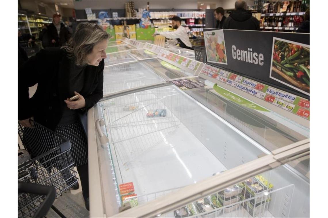 Leergekaufte Supermärkte: Eine Frau schaut sich in Berlin-Wilmersdorf eine fast leere Tiefkühltruhe für Gemüse an. Foto: Christoph Soeder/dpa