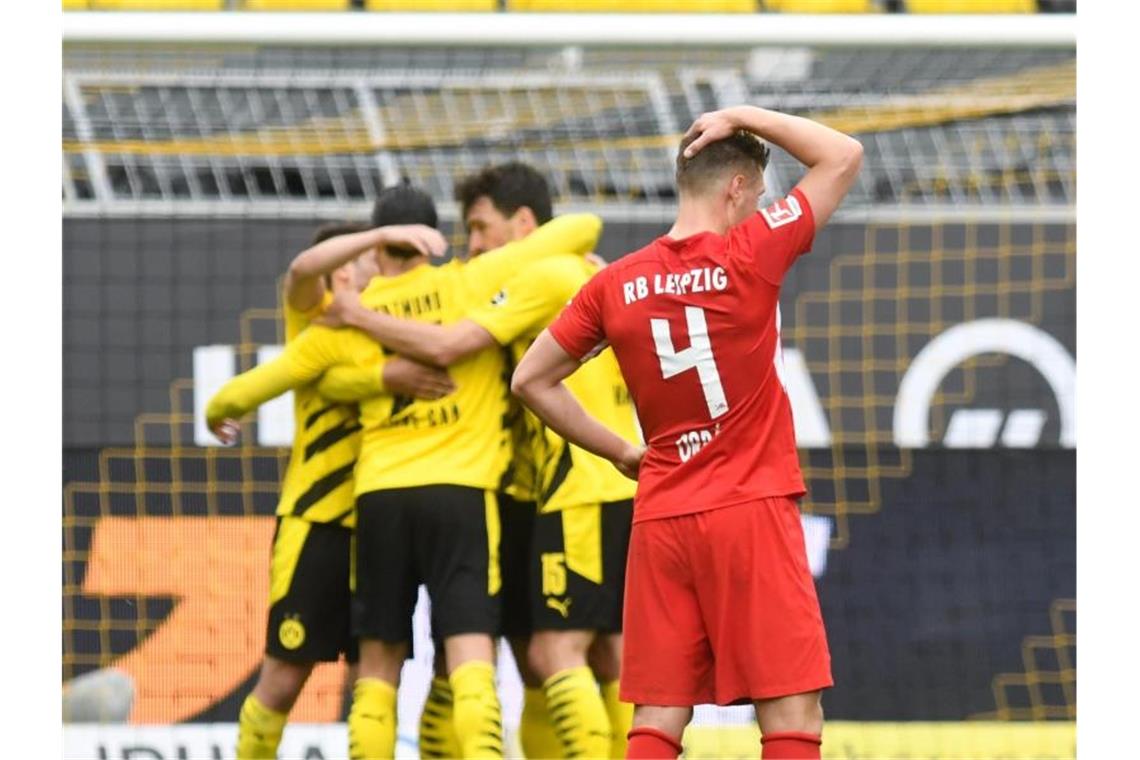 Leipzigs Abwehrspieler Willi Orban fasst sich nach der Niederlage beim BVB an den Kopf - im Hintergrund feiern die Dortmunder Spieler den Sieg. Foto: Bernd Thissen/dpa