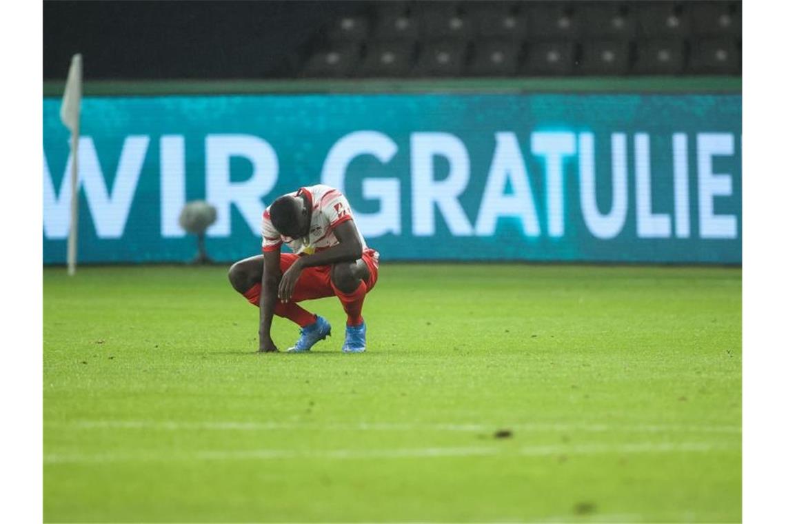 Leipzigs Dayot Upamecano hockt nach Spielende enttäuscht auf dem Spielfeld. Foto: Jan Woitas/dpa-Pool/dpa