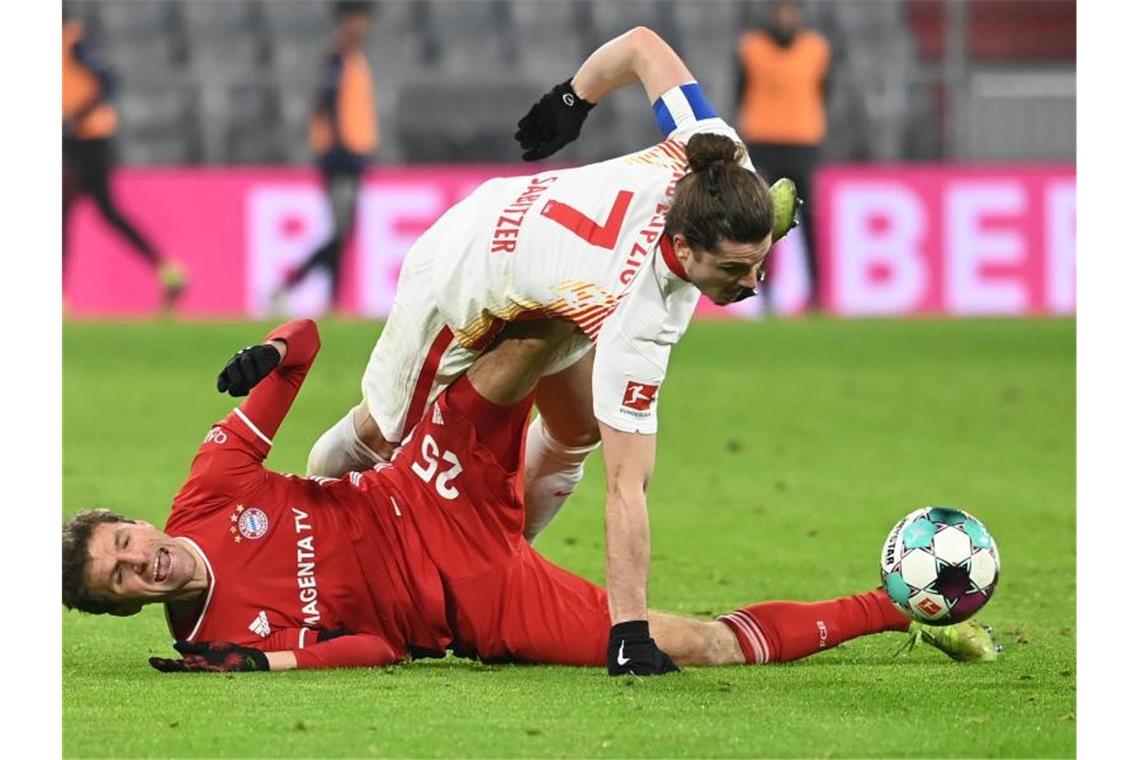 Leipzigs Marcel Sabitzer (o) versucht über dem am Boden liegenden Thomas Müller an den Ball zu kommen. Foto: Sven Hoppe/dpa