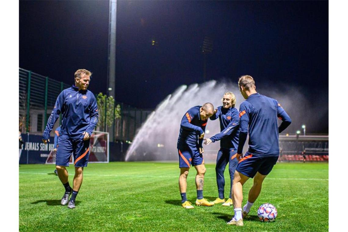 Leipzigs Trainer Julian Nagelsmann (l) schaut seinen Spielern beim Aufwärmen zu. Foto: Motivio/Thomas Eisenhuth/RB Leipzig/dpa