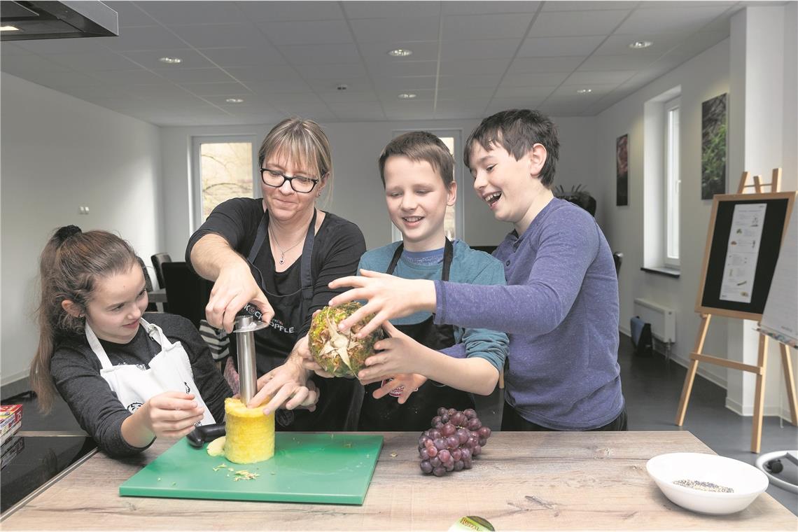 Selbstgemachtes für die nächste Party Lena, Niklas und Liam (von links) kämpfen mit dem Ananas-Schneider. Ulrike Stiehler (zweite von links) gibt Hilfestellung.Fotos: J. Fiedler