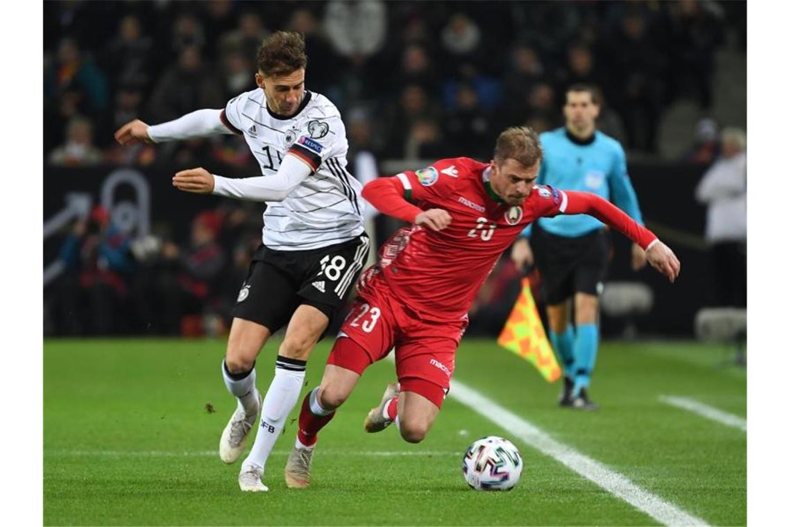 Leon Goretzka (l) bringt beim Kampf um den Ball Weißrusslands Pawel Nechajtschik zum Straucheln. Foto: Federico Gambarini/dpa