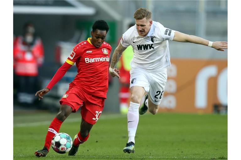 Leverkusens Jeremie Frimpong (l) und Augsburgs Andre Hahn im Zweikampf um den Ball. Foto: Tom Weller/dpa