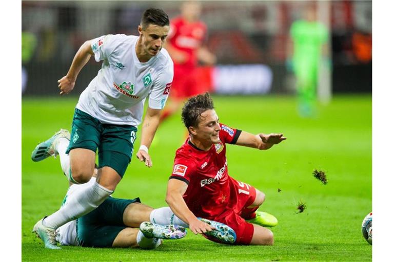 Leverkusens Julian Baumgartlinger (r) wird von Bremens Milot Rashica zu Fall gebracht, links läuft Bremens Marco Friedl. Foto: Rolf Vennenbernd/dpa