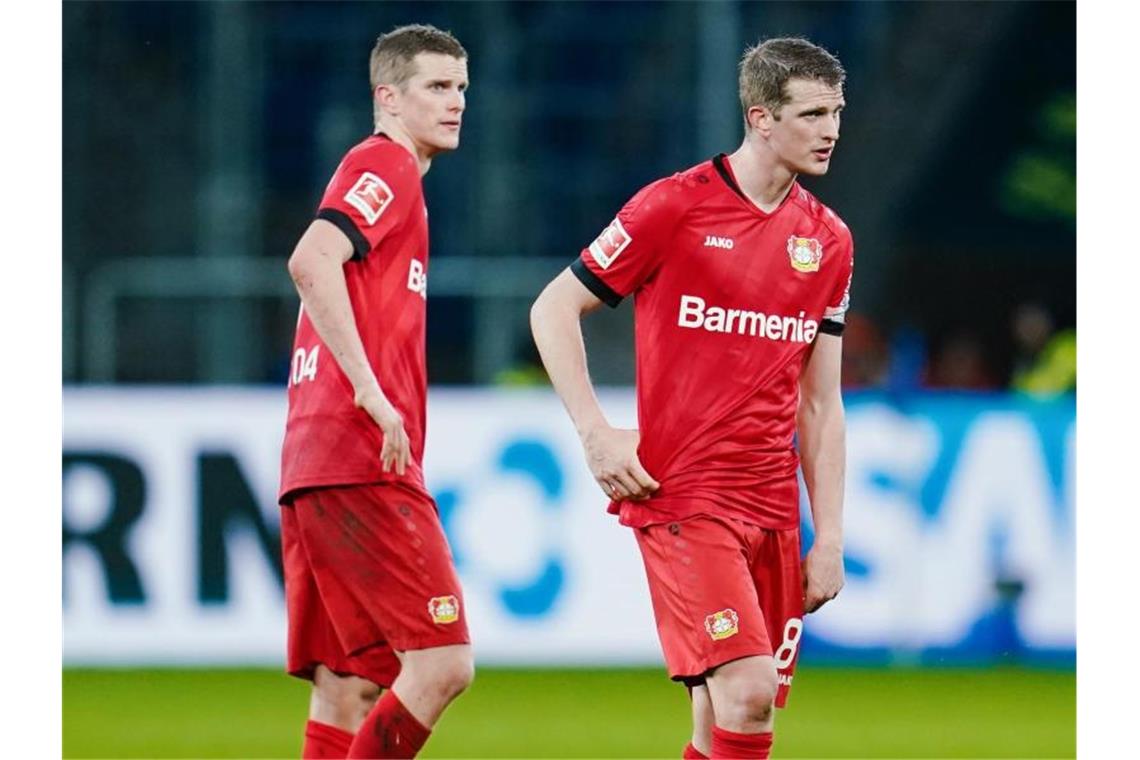 Leverkusens Sven Bender (l) und sein Bruder Lars stehen nach Spielende beim 1:2 gegen Hoffenheim ratlos auf dem Spielfeld. Foto: Uwe Anspach/dpa