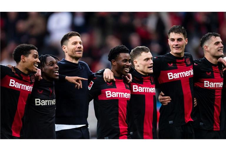 Leverkusens Trainer Xabi Alonso (3.v.l.) feiert nach der Partie mit den Spielern vor der Kurve.
