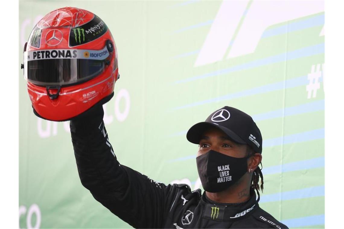 Lewis Hamilton feiert mit dem Helm von Michael Schumacher den Sieg auf dem Nürburgring. Foto: Bryn Lennon/Pool Getty/AP/dpa