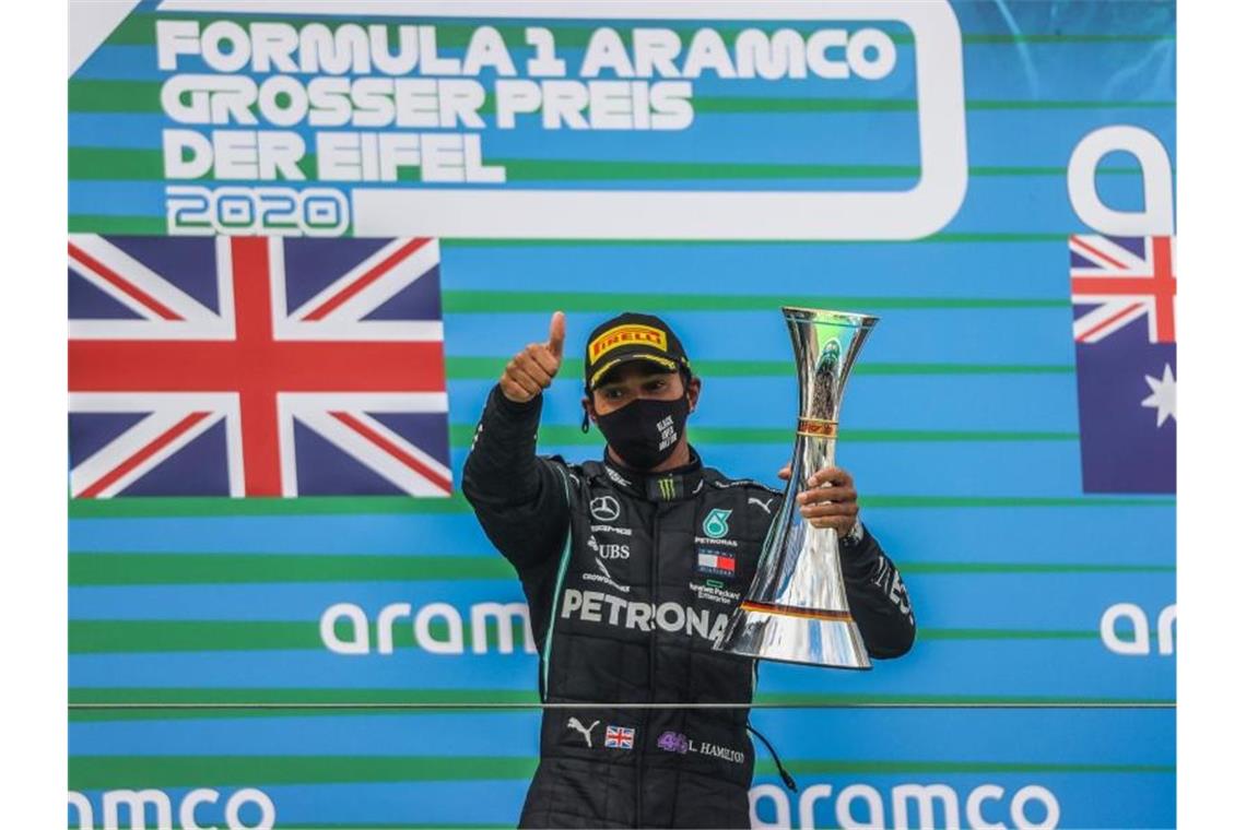 Hamilton siegt in der Eifel und stellt Schumacher-Rekord ein Lewis Hamilton feiert seinen Sieg auf dem Podest: Der Mercedes-Pilot hat den Großen Preis der Eifel gewonnen. Foto: Wolfgang Rattay/Pool Reuters/AP/dpa