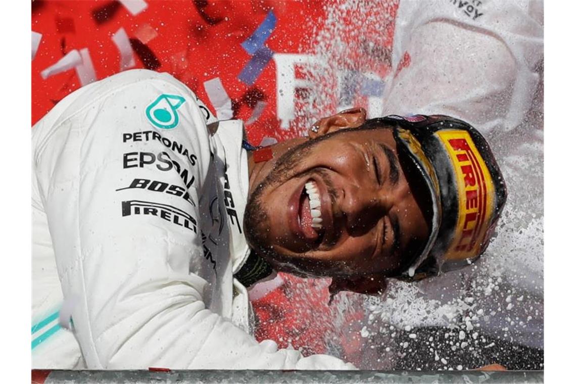 Lewis Hamilton genießt nach seinem sechsten WM-Titel die Champagnerdusche. Foto: Darron Cummings/AP/dpa