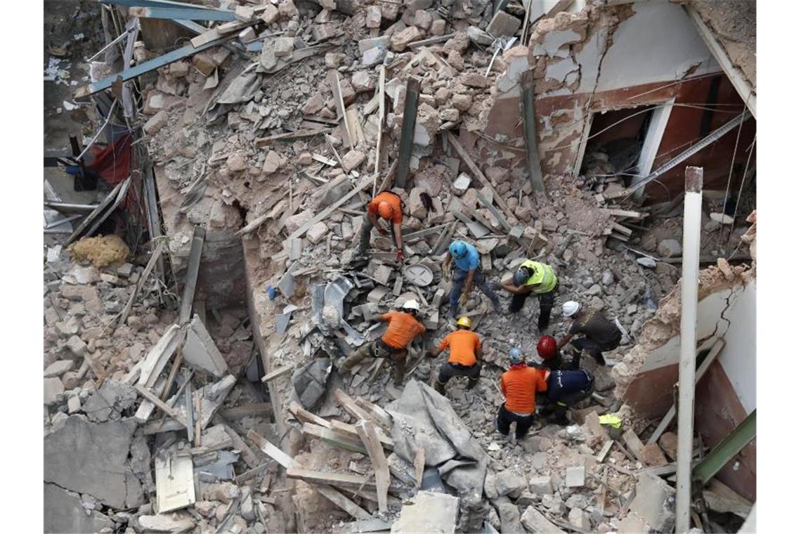 Libanesische und chilenische Rettungskräfte suchen in den Trümmern eines eingestürzten Gebäudes, nachdem sie Signale erhalten haben, dass es einen Überlebenden geben könnte. Foto: Hussein Malla/AP/dpa