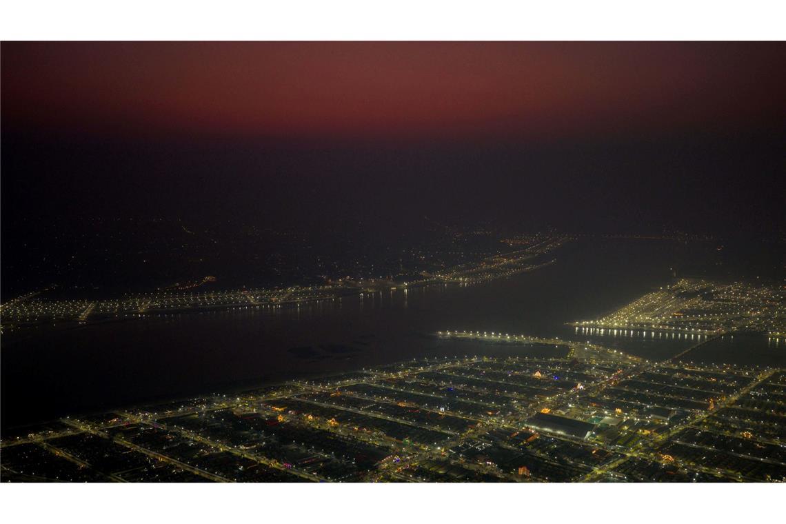 Lichter leuchten in provisorischen Zelten, in denen Pilger am Sangam, dem Zusammenfluss von Ganges und Yamuna und dem mythischen Fluss Saraswati, am Mauni Amavasya oder Neumondtag während des jährlichen einmonatigen religiösen Hindu-Festes Magh Mela in Prayagraj in Indien untergebracht sind.