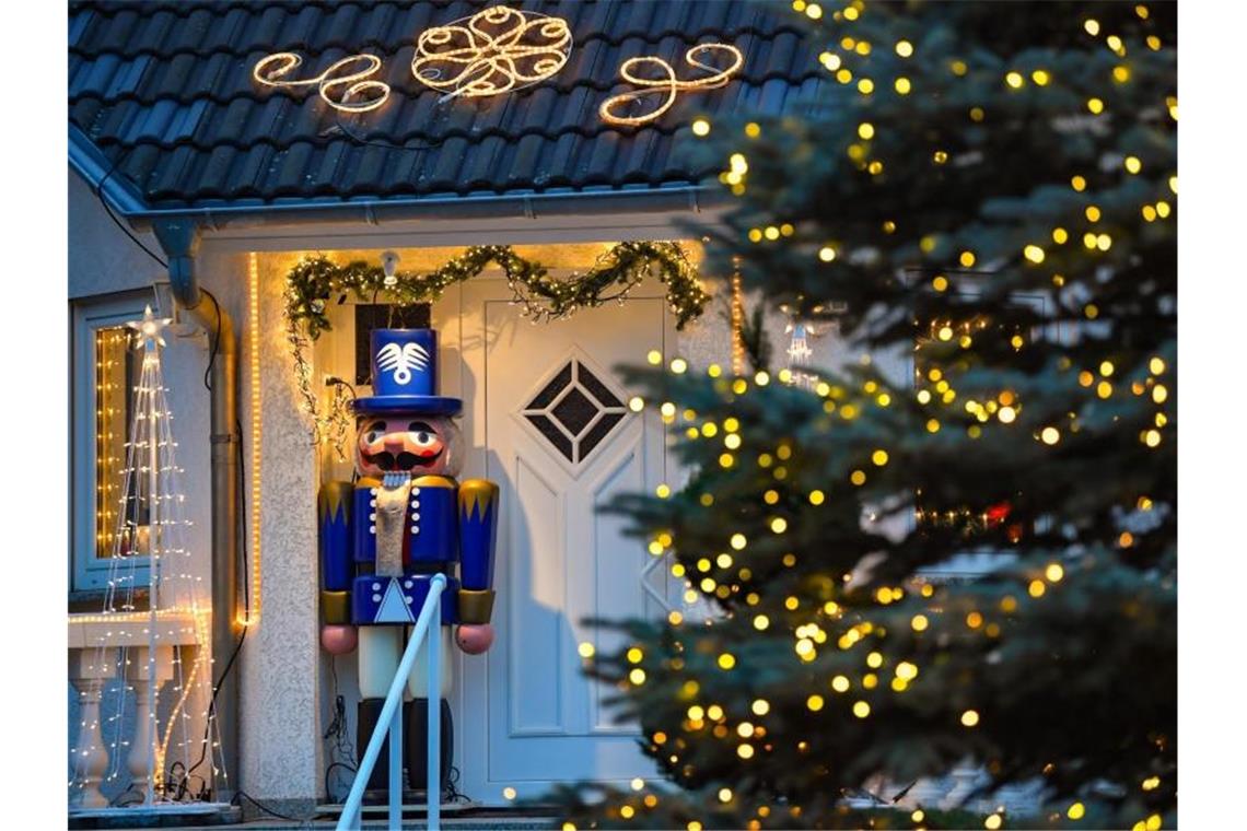 Lichterketten und ein großer Nussknacker stehen an einem weihnachtlich geschmückten Hauseingang. Foto: Patrick Pleul/zb/dpa