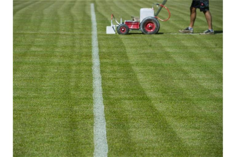 Linien werden auf den Rasen aufgebracht. Foto: Stefan Sauer/Archiv