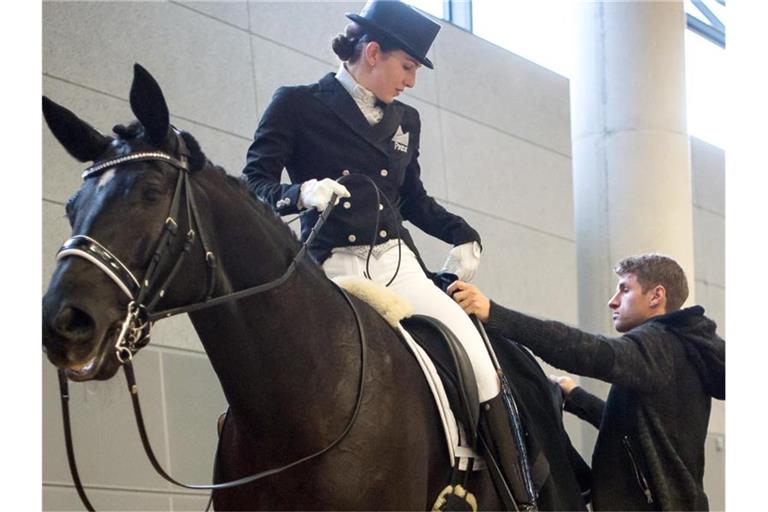 Lisa Müller steht mit ihrem Pferd in der Abreithalle. Foto: Peter Kneffel/dpa