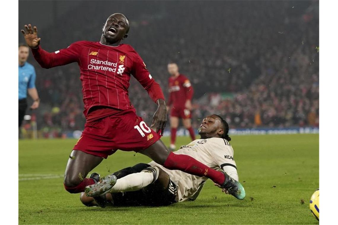 Liverpools Sadio Mane (l) wird von Manchesters Aaron Wan-Bissaka im Zweikampf von den Beinen geholt. Foto: Jon Super/AP/dpa