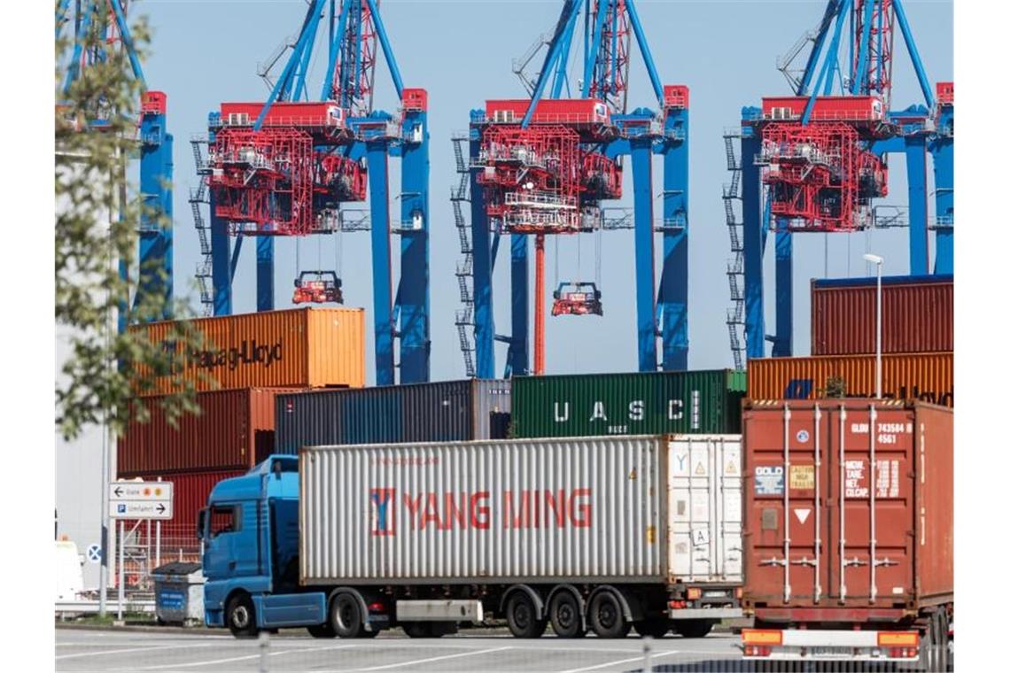 Weniger Wachstum für deutsche Exporte - Verbände in Sorge LKW liefern Container zum Beladen auf ein Containerschiff am Hamburger Tollerort-Terminal. Foto: Markus Scholz/dpa